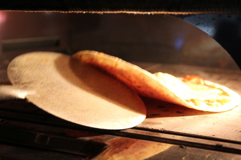Pizza wird mit dem Schieber aus dem Ofen geholt