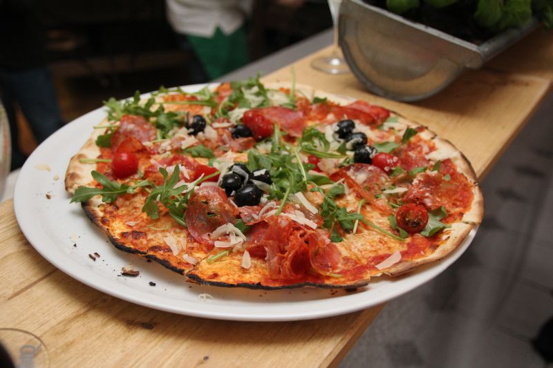 Frisch gebackene Steinofenpizza mit Salami, Oliven und Rucola